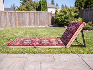 Side profile of red folding floor sunbed showing three 3 cm foam panels and metal backrest support leg