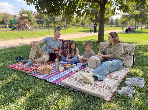 Family using red and beige Arabic sunbeds as portable floor seating at a park picnic